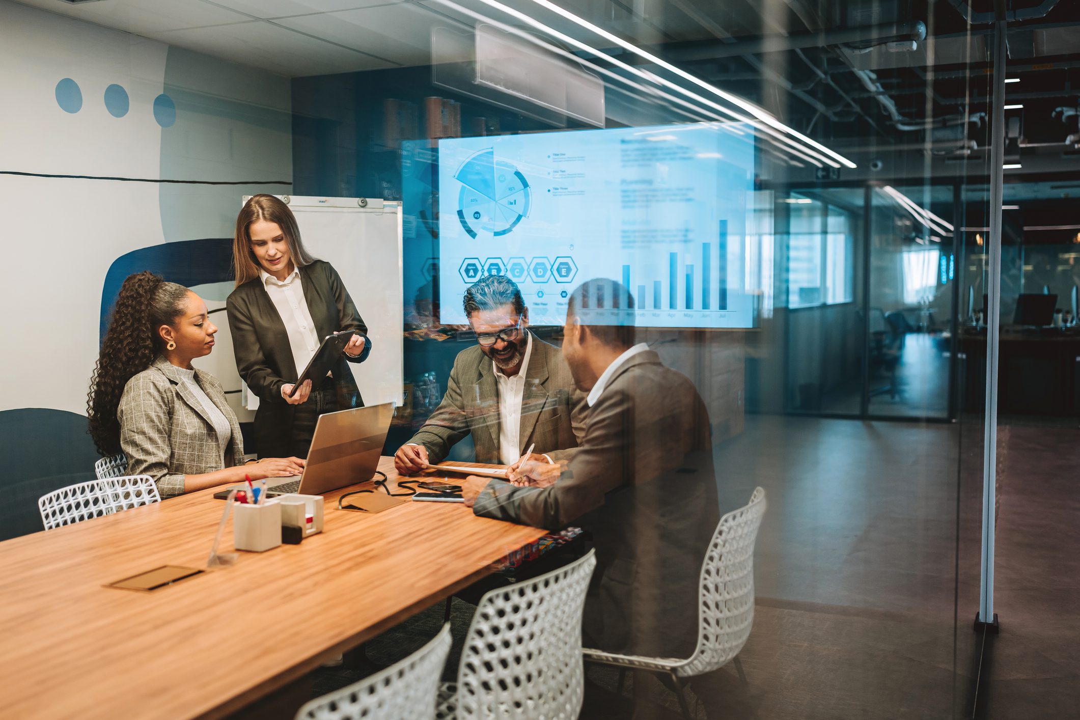 Business team collaborating around a table with digital data projections.